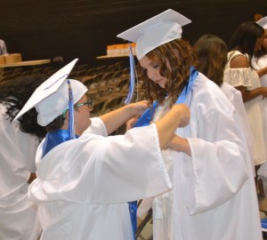 Renee Anderson (left) gives a helpful assist to Catherine Davenport by adjusting her sash prior to commencement.