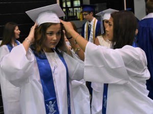 Madison Hamlet (right) makes sure Hunter Memmer’s cap is properly adjusted before graduation ceremony.