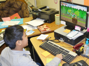 Adrian takes a quick break from schoolwork to demonstrate his game based off his illustrations and text from journal entries.