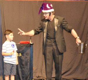 Magician Steve Kish pulls a quarter from behind a volunteer’s ear as part of his act as part of New Kent’s county fair.