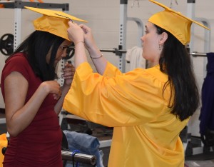 Kailin Holland (right) helps fellow classmate Sidney Adkins (left) adjust the tassel on her cap before graduation.