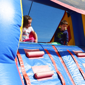Kids look back over a wall as part of a recently conquered part of an inflatable obstacle course.