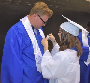 Taylor Goode (right) pins an emblem on the sash of classmate Dean Powell (left).