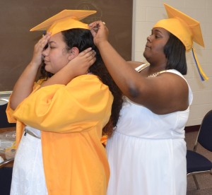 Jasmine Dabney (right) helps classmate Jazzlyn Smith adjust her graduation cap prior to the ceremony.