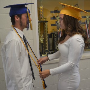 Ashley McDermott (right) helps Trevor Kelly adjusts his honor cords prior to the opening processional.