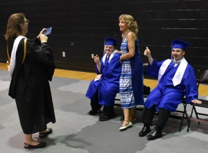 Shannon Bennett snaps a photograph of Kim Bashore and graduates Coleman Greene (left) and David Ramon (right) as they gives a thumbs up to show off their excitement for graduation.