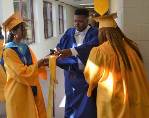 Daniell Tyler (center) gives some pre-graduation assistance in organizing his gown with the assistance of Nicole Allen (left) and Marissa Henderson (right).