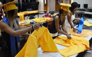(L to R) Shateka Brown, Markesha Hampton, and Daija Johnson apply finishing touches on their graduation gowns before the ceremony.