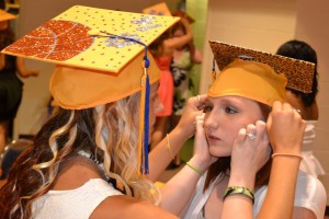 Jodilynne Skipper (right) gets an assist from Cheyenne Davis in adjusting her cap.