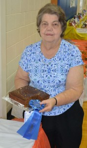 Joy Starkey (above) proudly displays her blue ribbon as her baked dish was named “Best Gingerbread of Charles City” in this year’s contest. Her success undoubtedly will add her name onto the wall of “Best in Charles City” exhibit, a display highlighted by pictures of winners who appeared in the Chronicle (below).