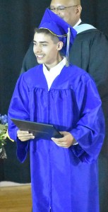 Orion Wilson is all smiles as he holds his diploma proudly for an on-stage photo.