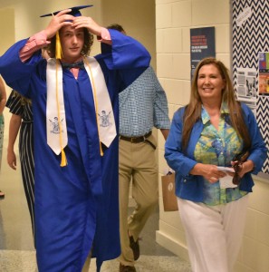 Baylor Wayman (left) straightens his mortarboard as he walks down the hallway to the auditorium.