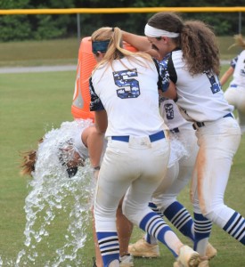 Lady Trojan head coach Maria Bates can't escape the traditional celebratory bath as players douse her with water.