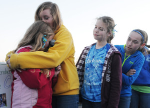 Ellie Ferrell is comforted by big sister Caitlin Ferrell as she fights back tears while addressing the crowd about the good times she spent with her friend, Nichelle Jones. Looking on and awaiting their turn to take the microphone are Morgan Setzer and Madison Williams.
