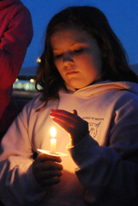 Ginna Simmons shields her candle from the wind during the ceremony. 