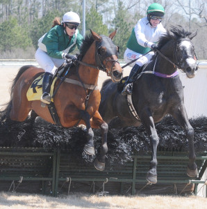 Horses and riders clear one of the fences in the first of five races.