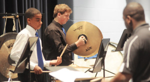 Part of the middle and high school band's percussion section is shown performing in concert in the auditorium.