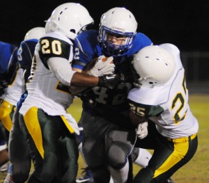 New Kent running back John Elswick plows through tackling attempts by Bruton's DeAndre Kissoon (20) and D'Aundre Laffoon.