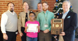 Jawa Johnson (center), a student at George Watkins Elementary, smiles as she accepts her certificate . Pictured with her are (l to r) principal Russ Macomber, Corporal Heath Jenkins NKSO, fifth grade teacher Ben Hindman, and Rula.